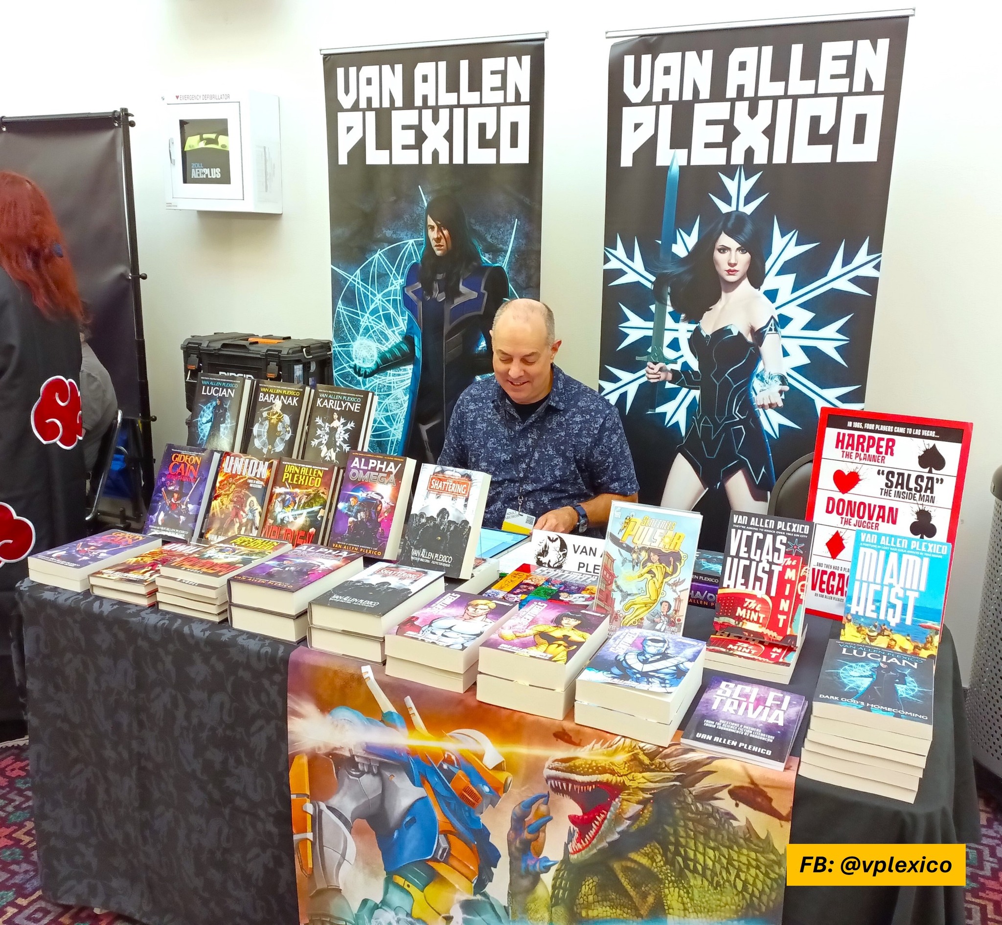 Author table with books at a convention.